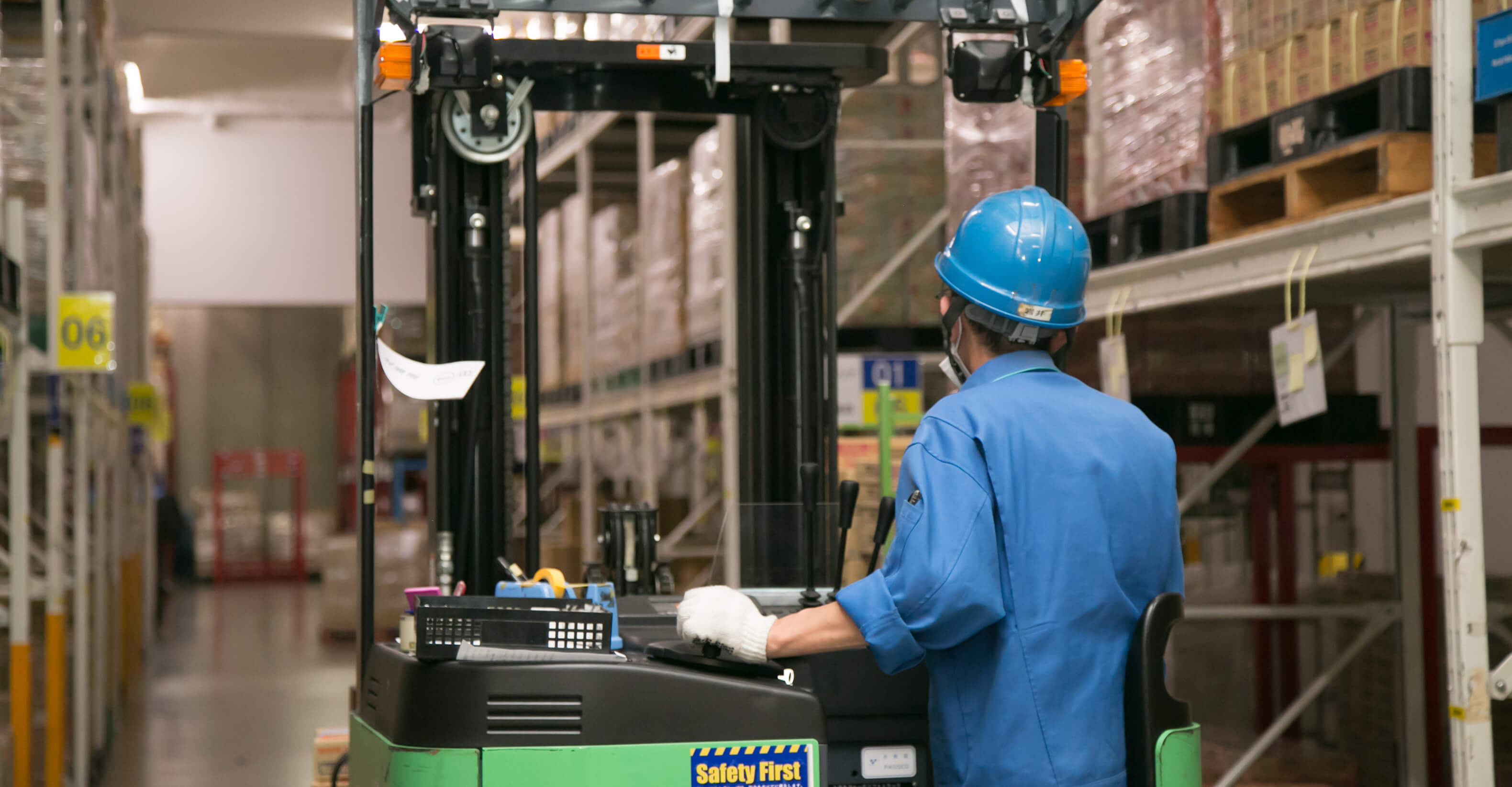 フォークリフトで荷物を荷台に積む女性